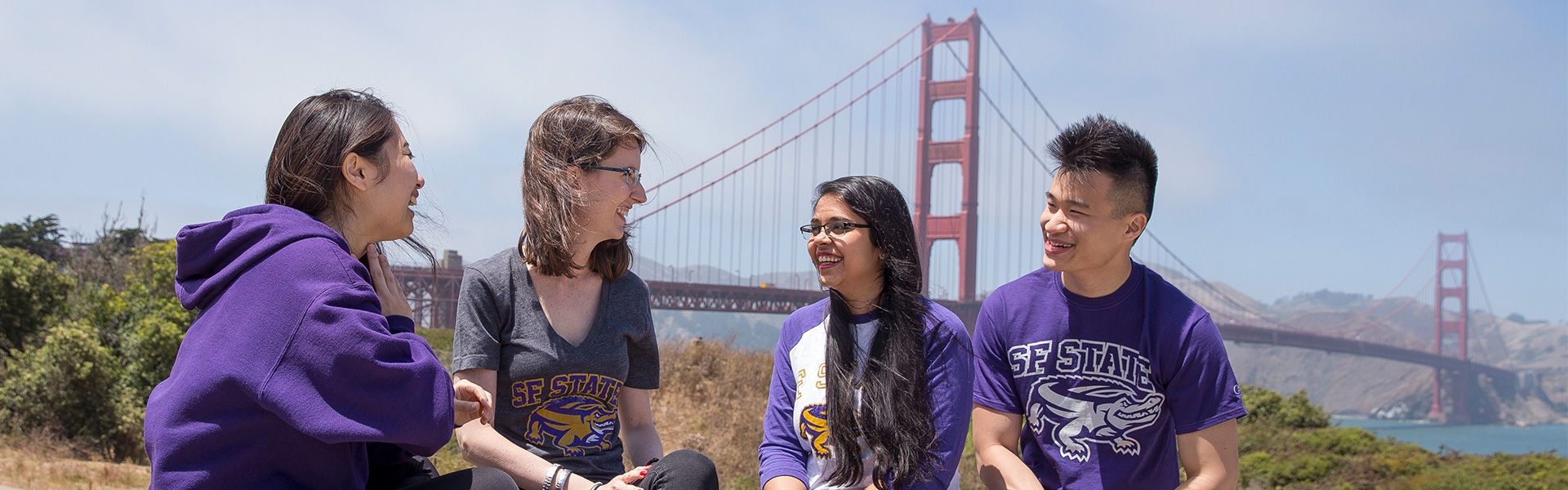 SF State students wearing SF State merchant sitting in front of Golden Gate Brigde